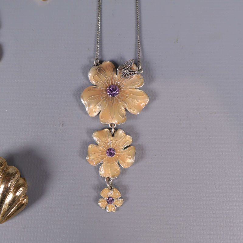 Halsband med tre guldblommor och lila stenar