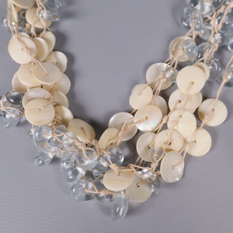 Närbild på halsbandets snäckskivor och klara pärlor