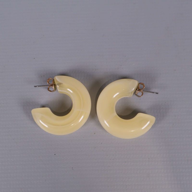 Ett par krämfärgade, blanka örhängen i ringform