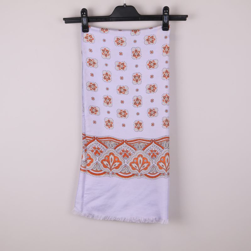 Ljus sjal med orange blommönster och bård hänger på galge