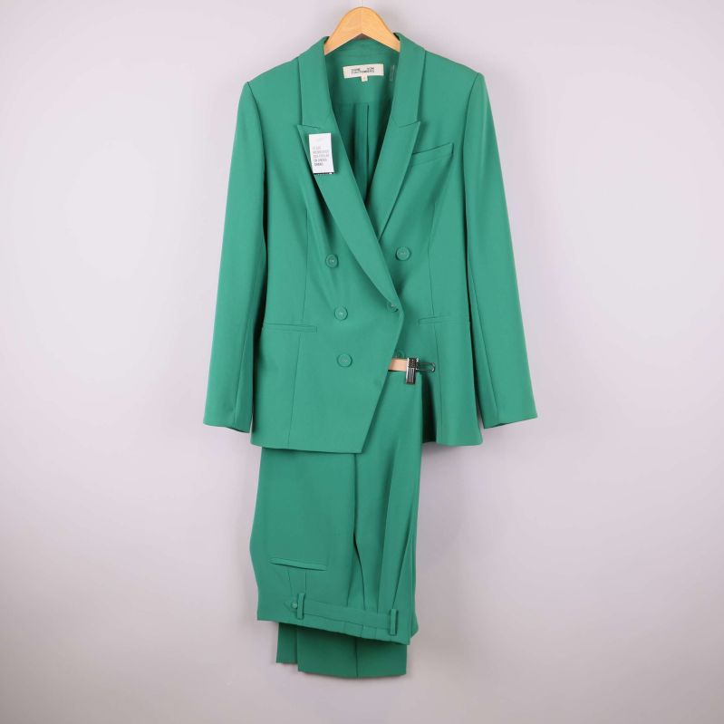 Grönt kostymset med kavaj och byxa hänger på galge