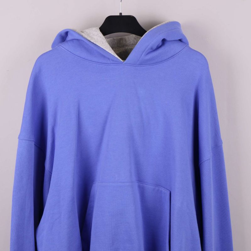 Framstycke av blå hoodie med synlig magficka och huva