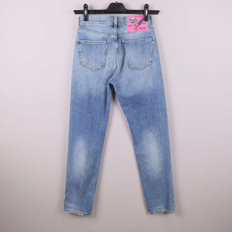 Baksidan av jeans med rosa broderad lapp på fickan