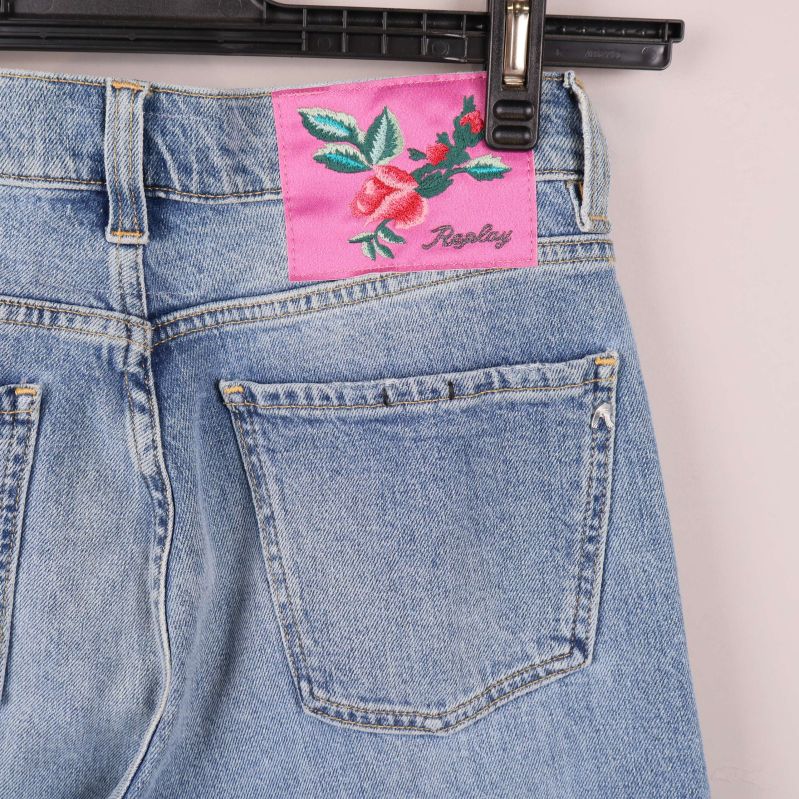 Närbild på rosa broderad patch med ros på bakfickan