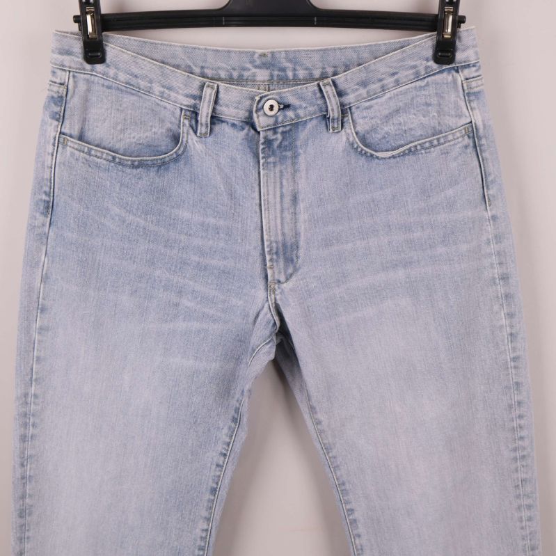 Närbild på jeansens framsida med knäppning och fickor