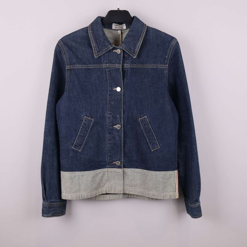 Mörkblå jeansjacka med kontrastfärgad kant nedtill, hängande på galge