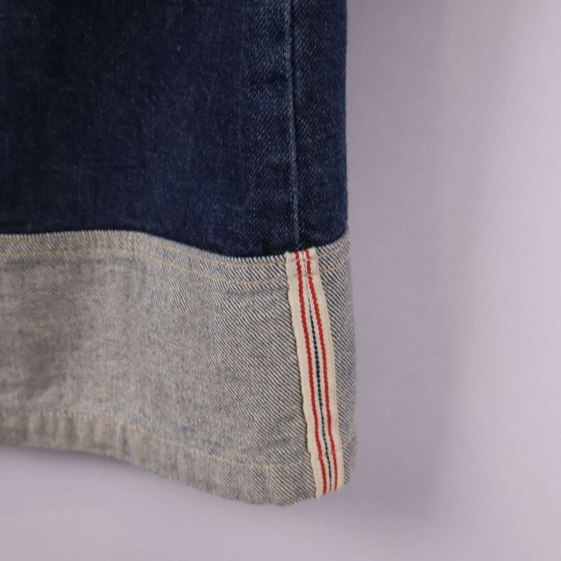 Närbild på sömdetalj och kontrastkant i ljus denim med röd rand