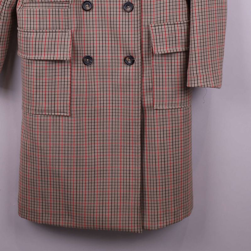 Närbild på fickor och nederkant av rutiga kappan