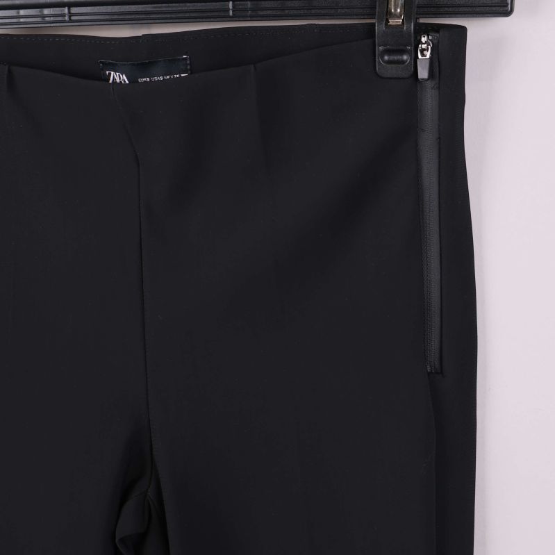 Närbild på sidodragkedja vid midjan på svarta byxan