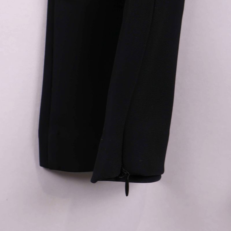 Närbild på dragkedja vid benslut på svart smal byxa