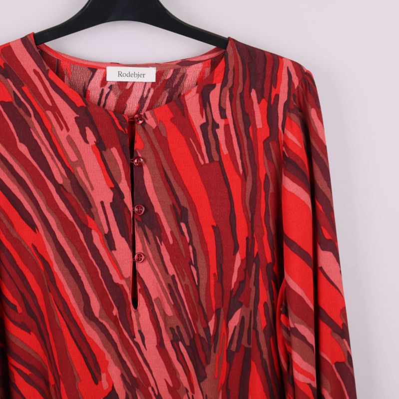 Närbild på blusens knäppning och mönstrad tyg framtill