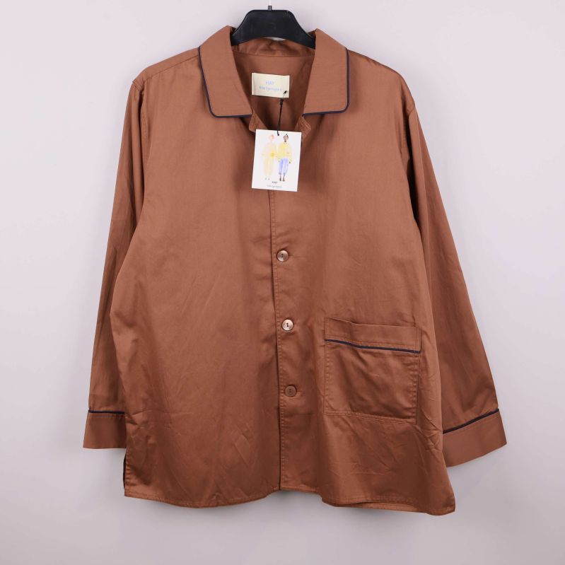 Brun pyjamasskjorta med svarta kontrastband hänger på galge