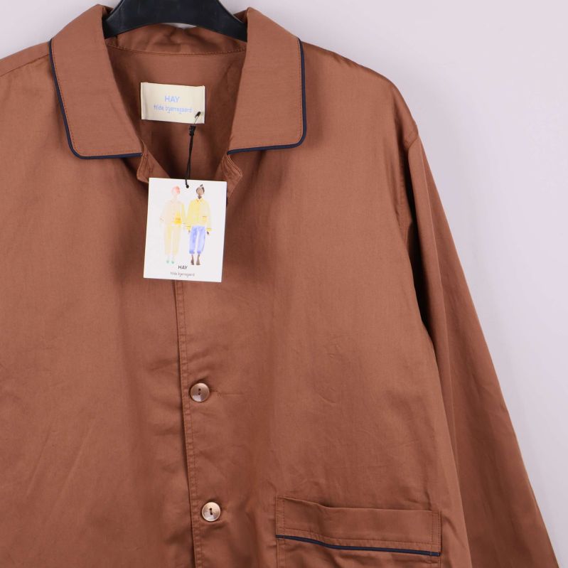 Bröstficka och knappar på brun pyjamasskjorta visas i detalj