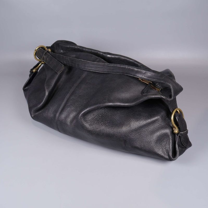 Undersidan av svart läderväska med stora mässingsringar