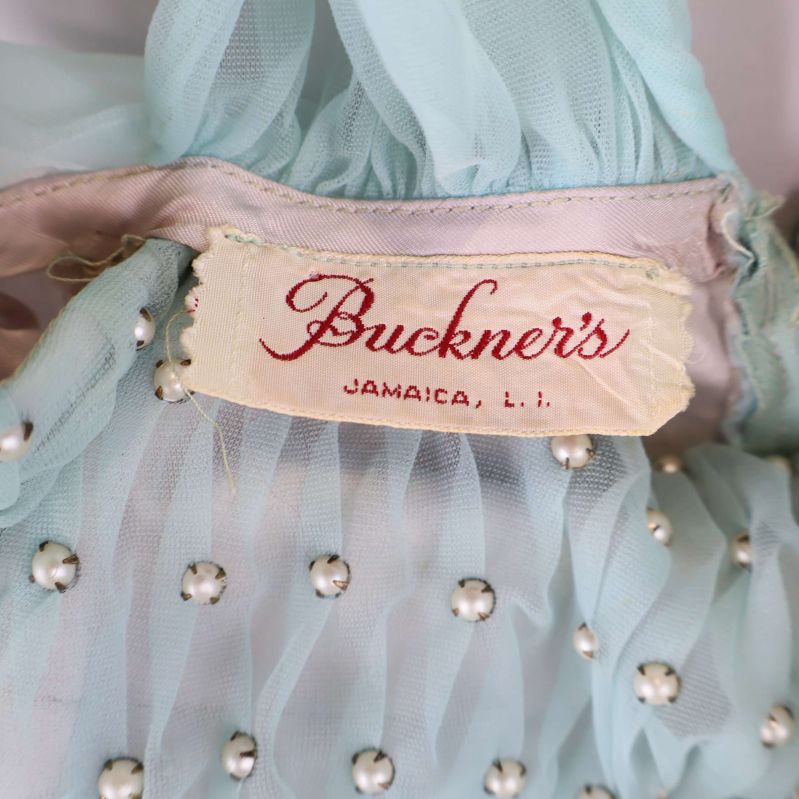 Buckner's etikett insydd i ljus turkos tyg med pärlor