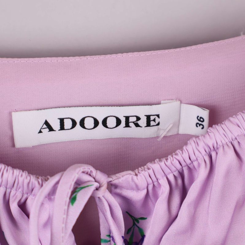 Närbild på Adore etikett och storlek 36 i lila klänning