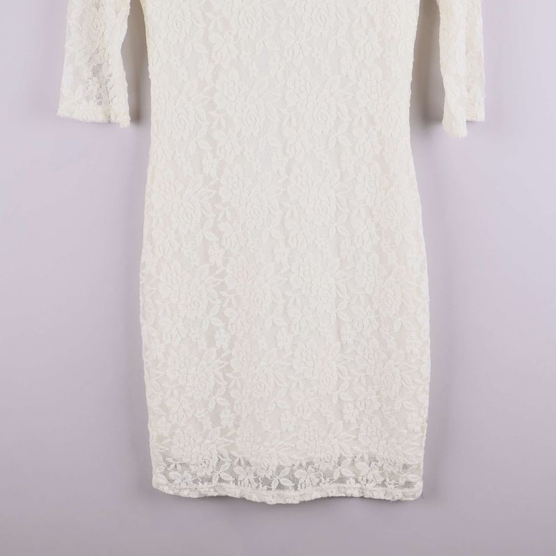 Närbild på nederdelen av vit spetsklänning