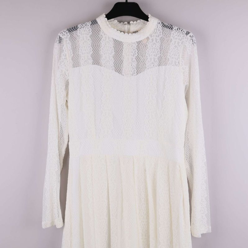 Detaljbild på klänningens spets, överdel och ärmdesign