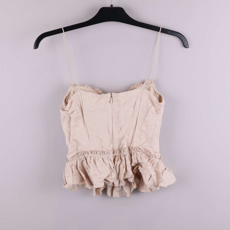 Baksidan av ljusbeige bustier med volang, dragkedja synlig