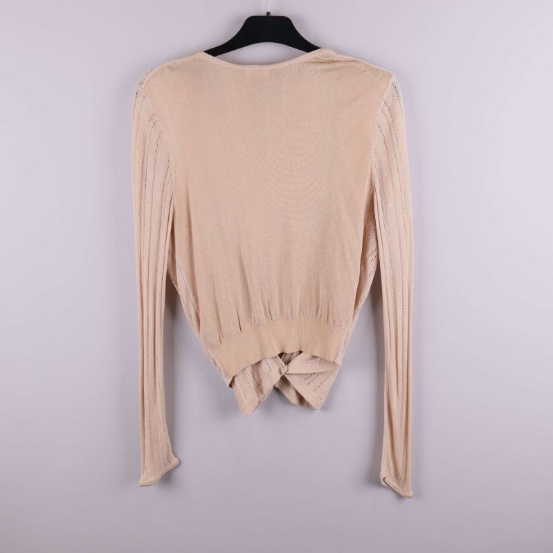Baksida av beige omlottkofta med ribbade detaljer