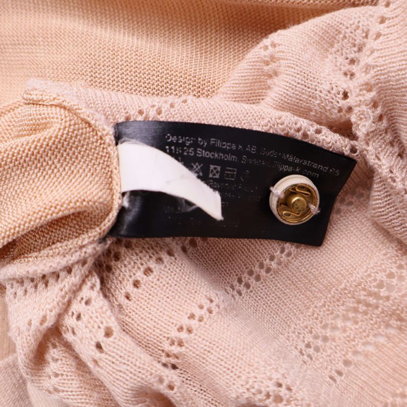 Tvättrådsetikett och knapp fäst på insidan av koftan