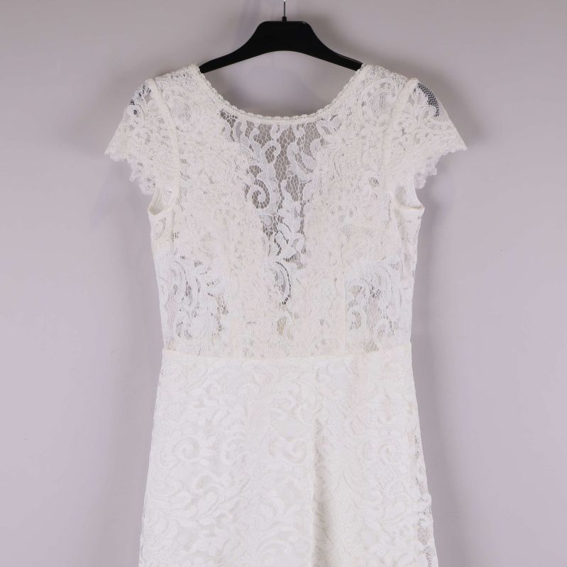 Övre del av vit spetsklänning med spetsdetaljer och kort ärm