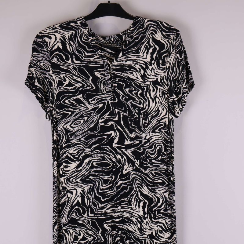 Detaljbild på överdelen av svartvit klänning med knappslå