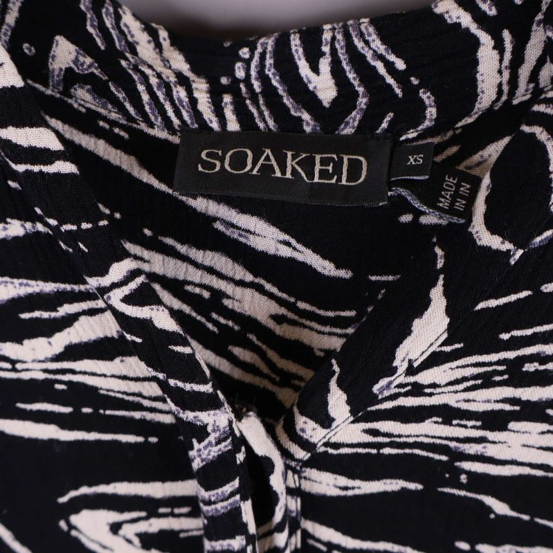 Närbild på Soaked-märke och storleksetikett XS i klänningens halslinning