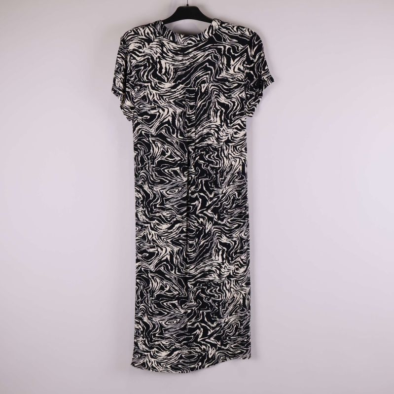 Svartvit mönstrad klänning fotograferad bakifrån på galge