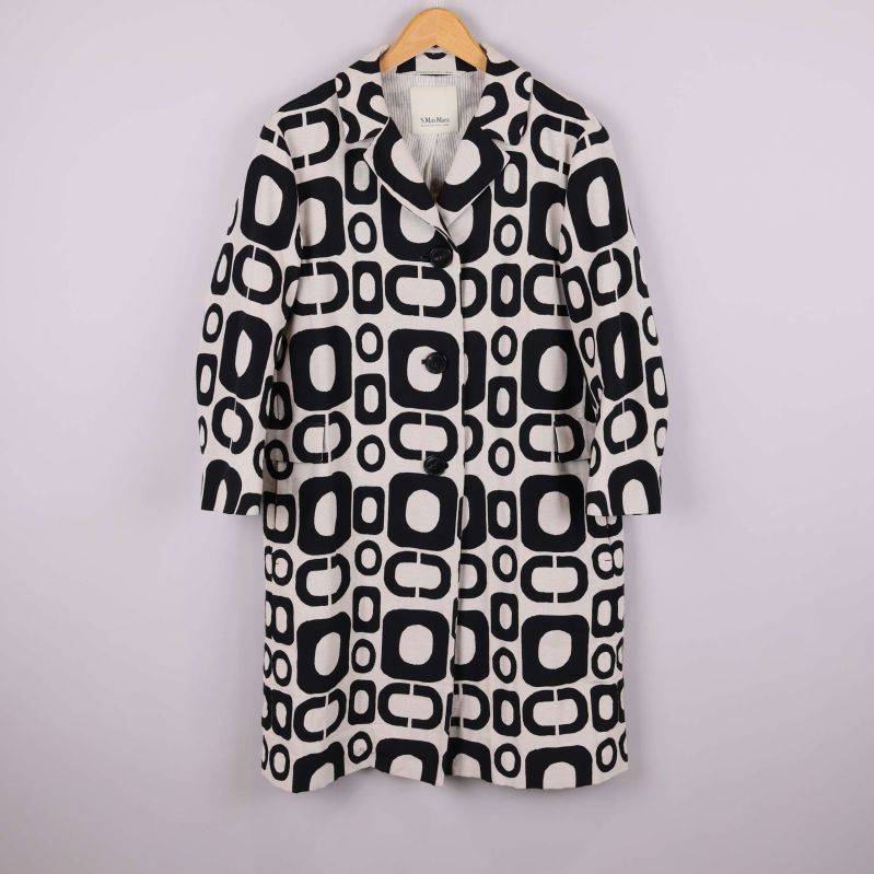 Kappa med svartvitt grafiskt mönster framifrån på galge