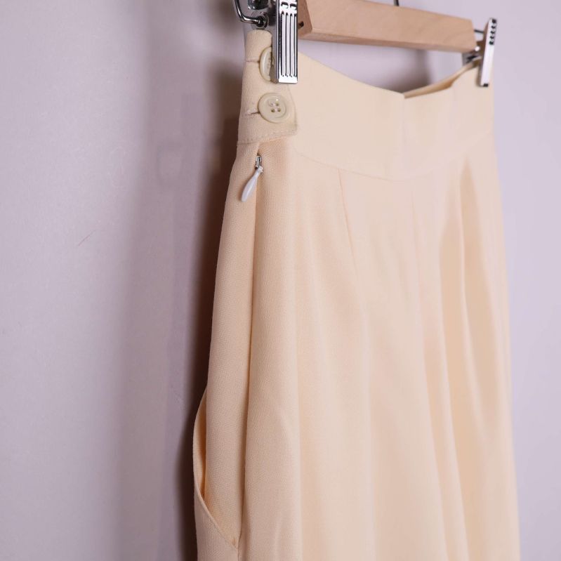 Närbild på midja och knappdetalj på beige byxa