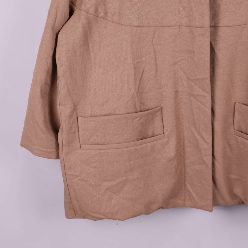 Närbild på de två framfickorna på beige jacka