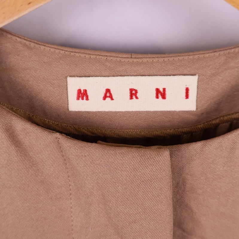 Närbild på Marni-märket i halsringningen på beige jacka