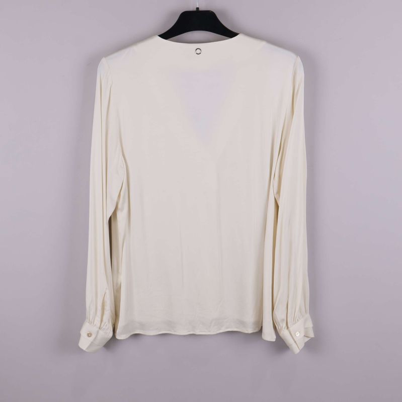 Blusens baksida med knapplösa manschetter syns tydligt