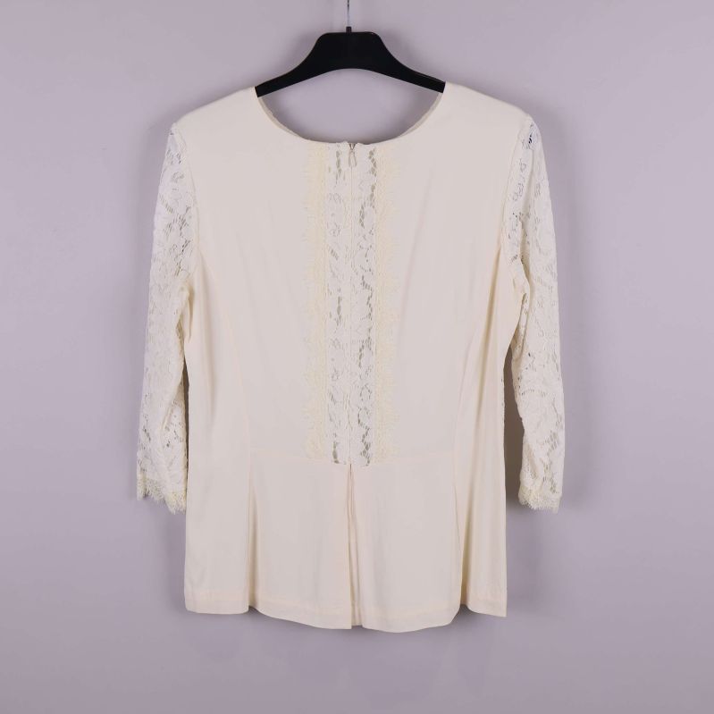 Baksida av ljus spetsblus med dragkedja och spetsdetalj