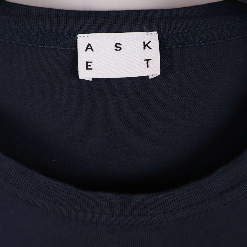 Närbild på Askets logotyp i nacken på t-shirten