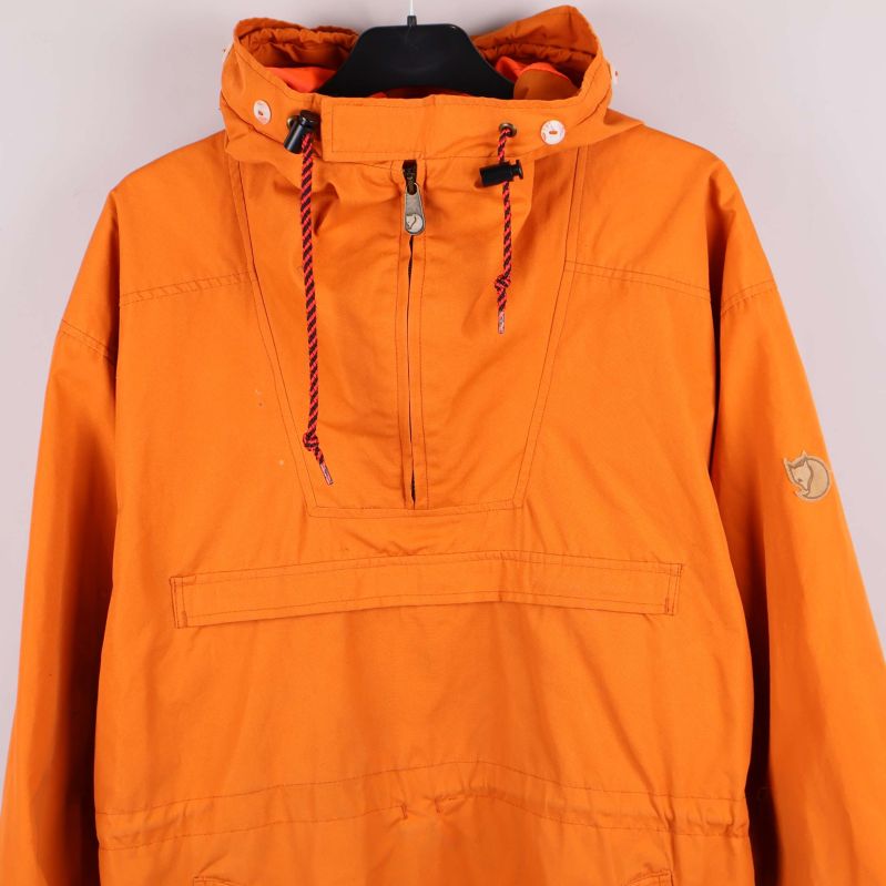 Närbild på orange anorakens huva med snören och dragkedja