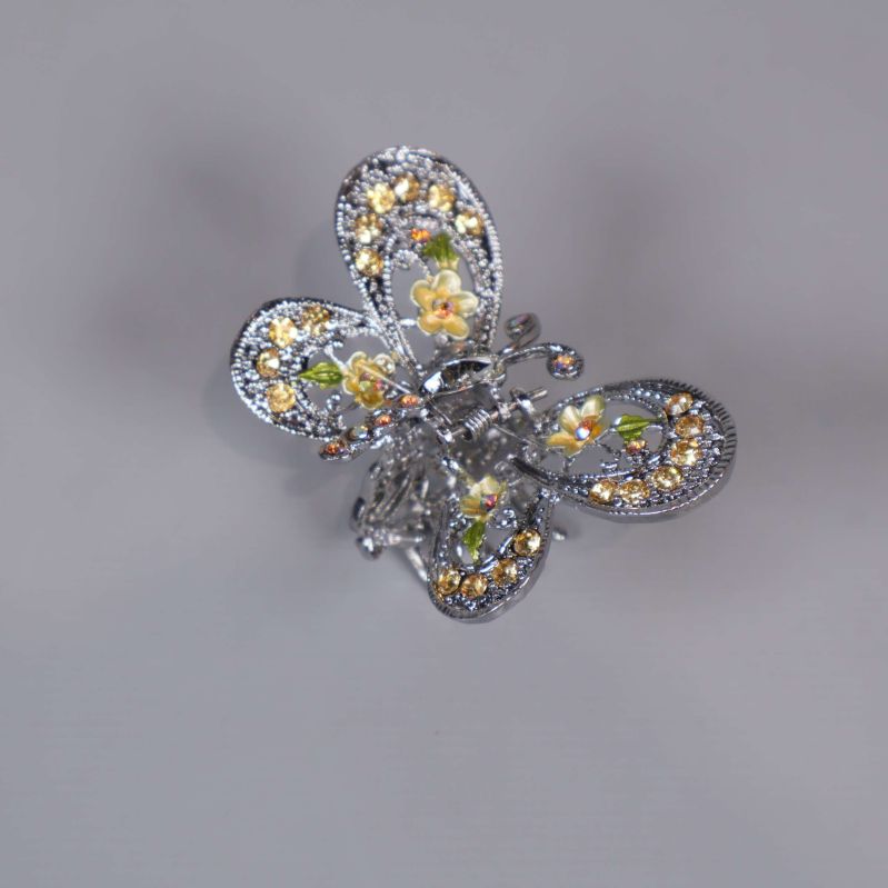 Närbild på broschens vingdesign med gulblommiga detaljer