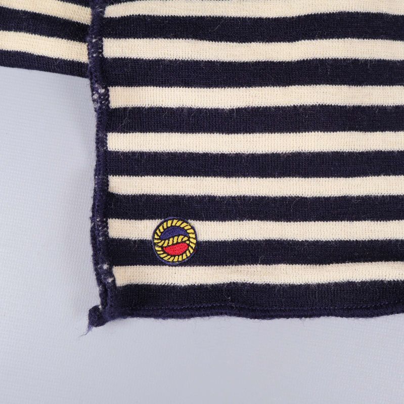 Närbild på broderad detalj i hörnet av randig halsduk