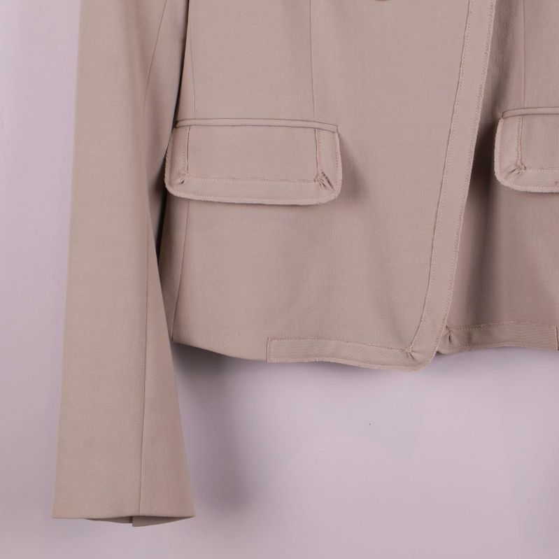 Närbild på ficka och ärm i beige kavaj