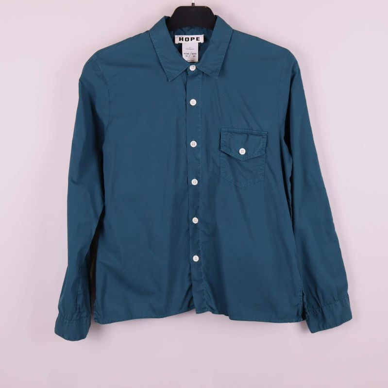 Blå skjorta med vita knappar och bröstficka