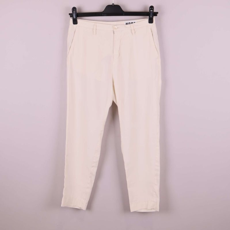 Baksidan av vita byxor på galge mot ljus bakgrund