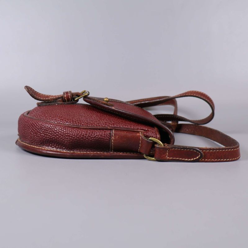 Brun läderväska sedd från sidan på platt underlag