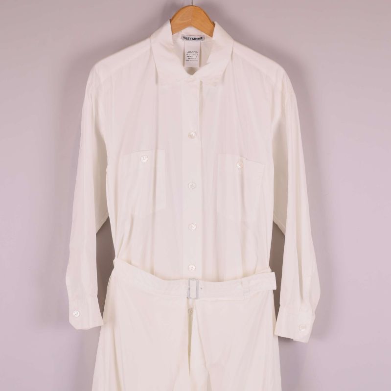 Närbild av övre delen på vit skjortklänning med knappar och fickor