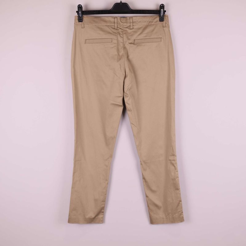 Beiga byxor upphängda mot ljus bakgrund, bakifrån