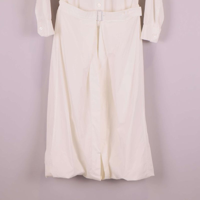 Närbild på kjoldel av vit klänning med bälte i midjan