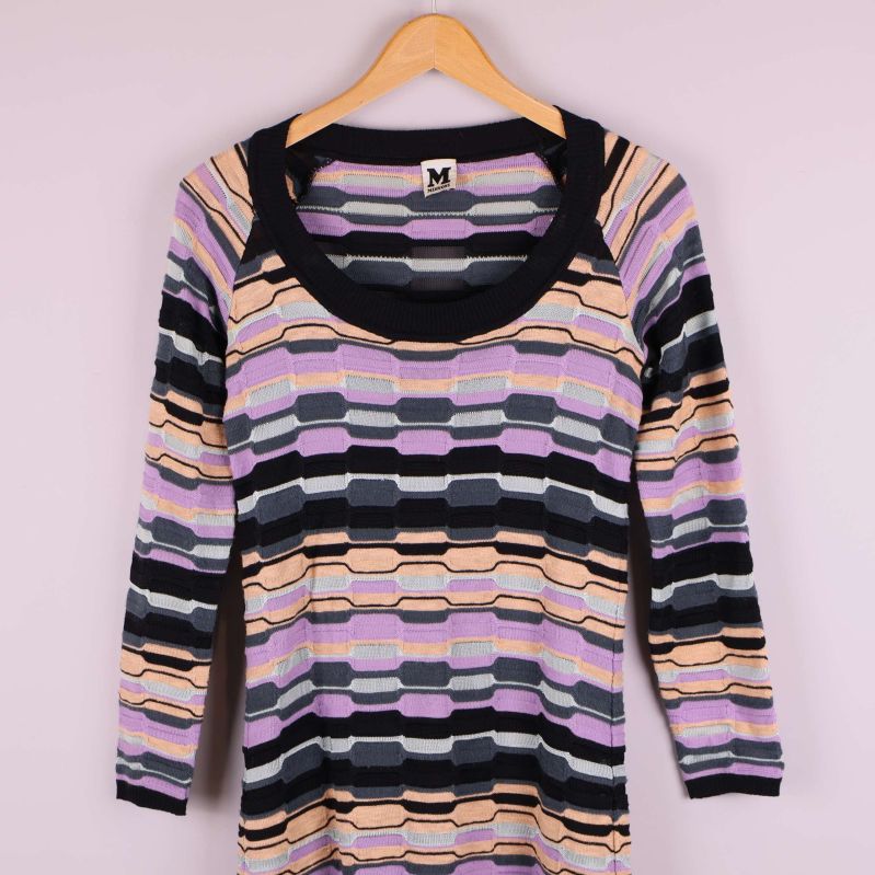 Närbild på halsringning och axel på mönstrad stickad klänning