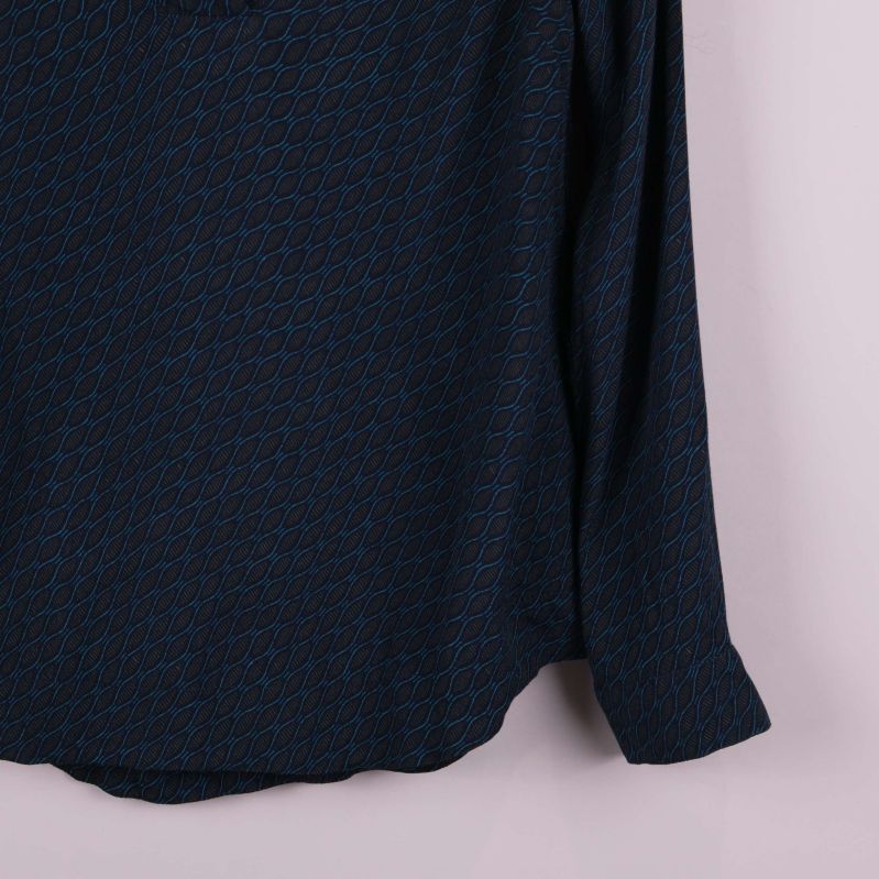 Ärm- och nederkantsdetalj av blåmönstrad topp