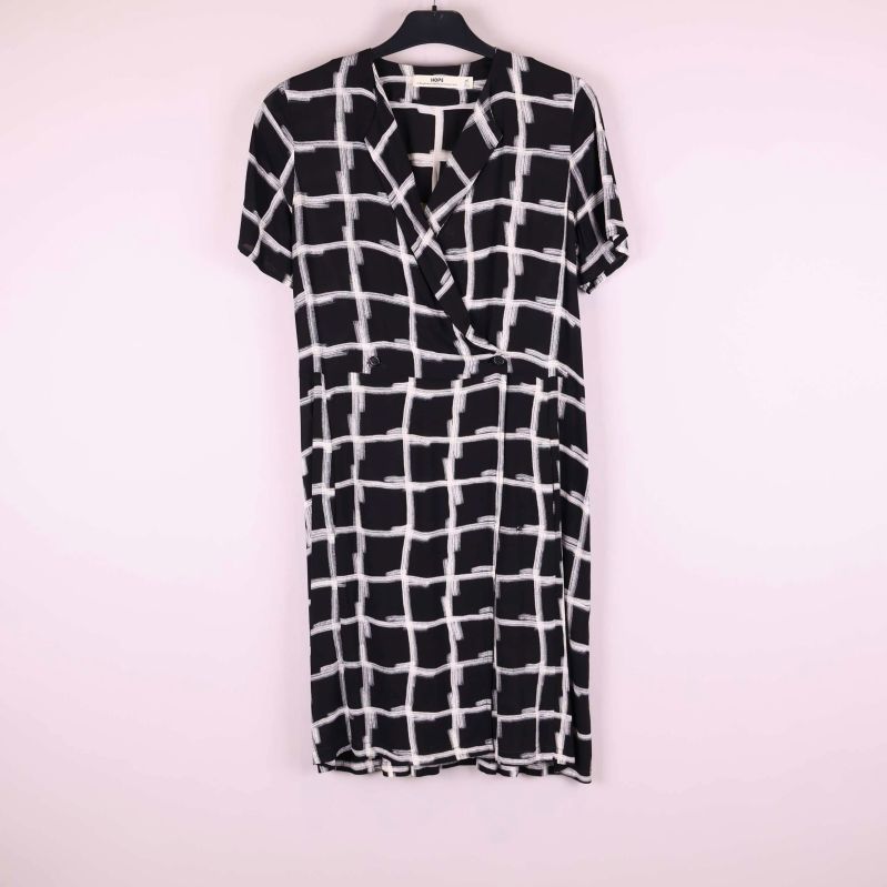 Kortärmad omlottklänning med svartvitt rutmönster hänger på galge