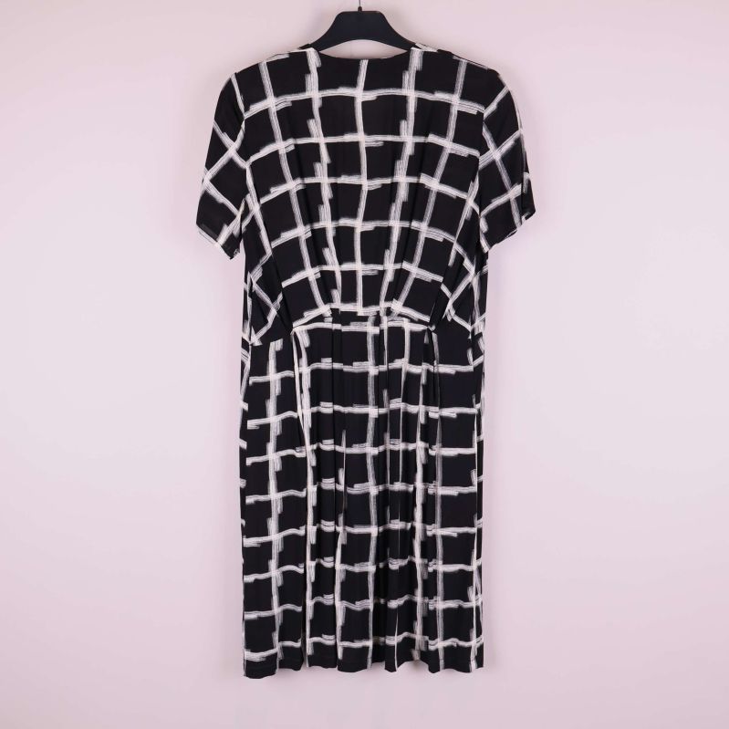 Baksida på svartvitt rutmönstrad omlottklänning på galge